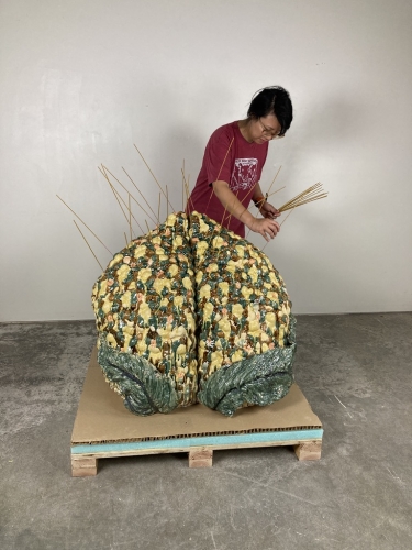 Cathy Lu placing incense on her sculpture,&nbsp;Untitled (Tall Peach Incense Holder), 2021.